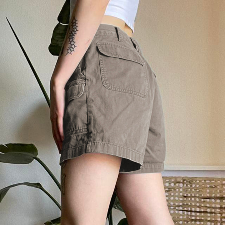 Une personne porte un short cargo évasé mi-long gris pour femme. Le short a des poches latérales et une fermeture à bouton et à glissière. Parfait pour un look décontracté et stylé. Disponible du S au L.