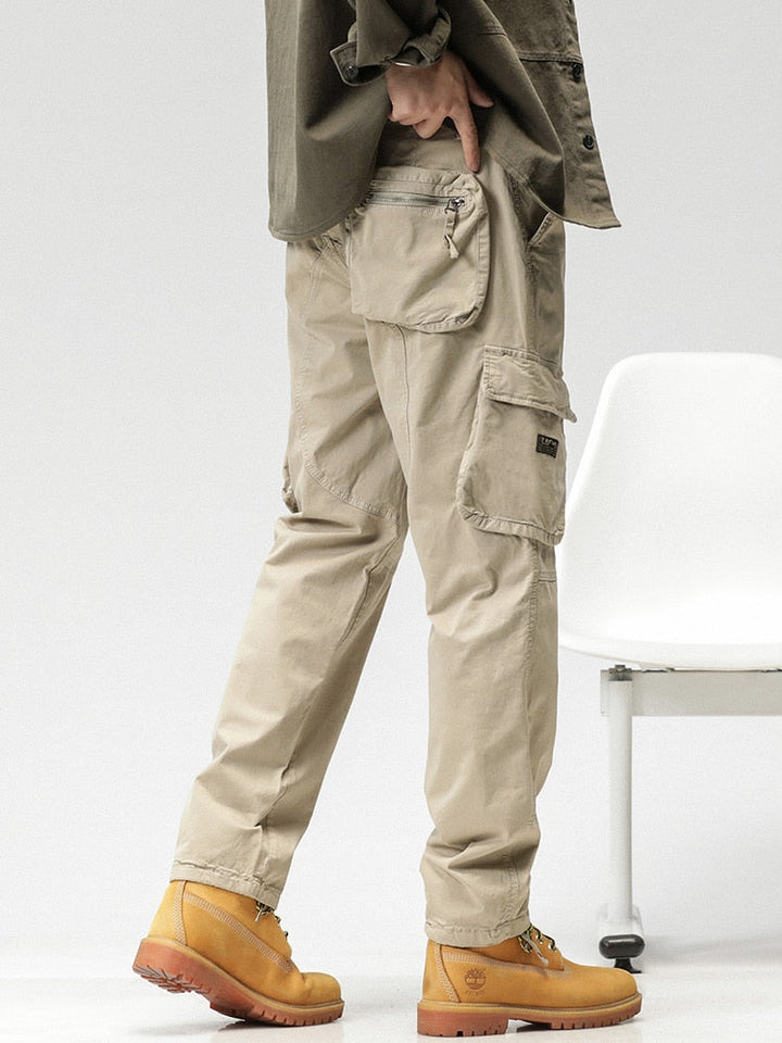 Un homme porte un pantalon cargo ample coupe droite beige avec des chaussures jaunes. Les poches sur les côtés ajoutent fonctionnalité et style.