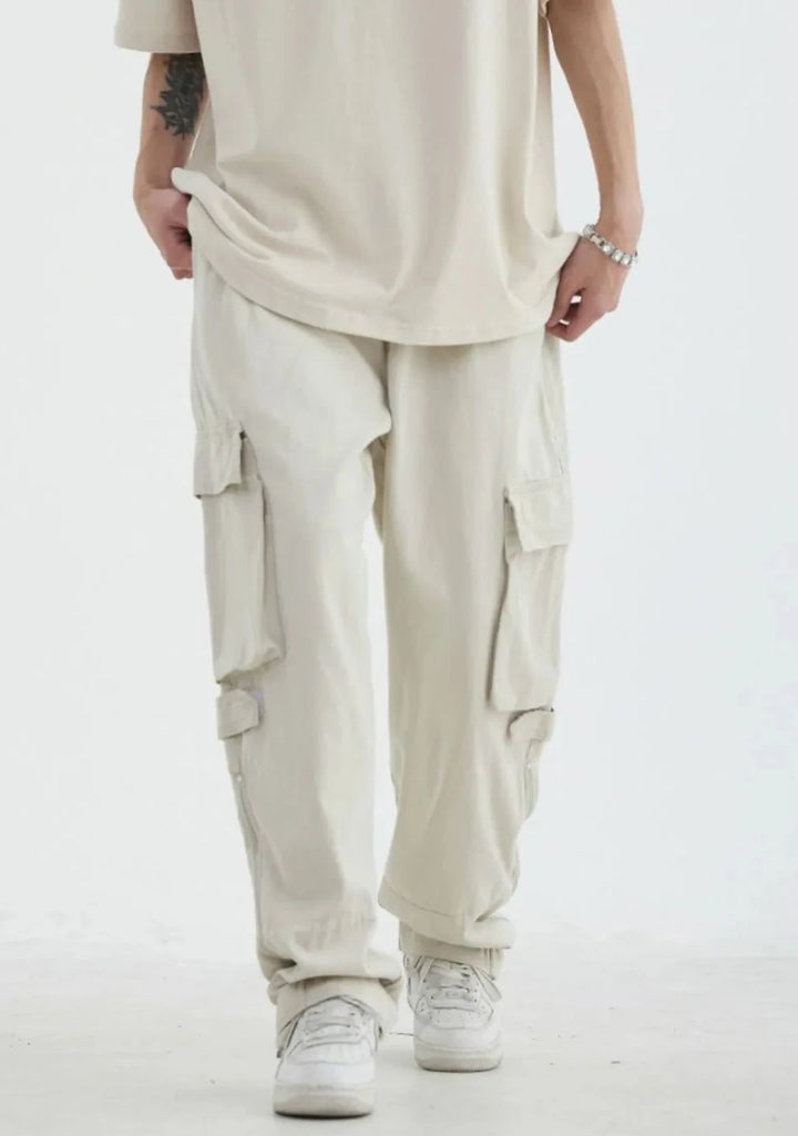 Un homme portant un pantalon blanc cargo avec poches, en coton 100%. Style décontracté et ample, inspiré de la mode japonaise vintage. Tailles disponibles : M à 2XL.