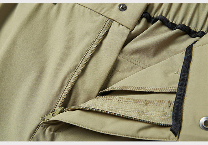 Un gros plan sur une fermeture éclair d'un pantalon cargo technique coupe droite kaki clair pour homme. Les nombreuses poches zippées ajoutent une touche de sécurité et de fonctionnalité. Parfait pour les activités extérieures grâce à sa composition en nylon et spandex à séchage rapide. Tailles disponibles du M au 8XL.