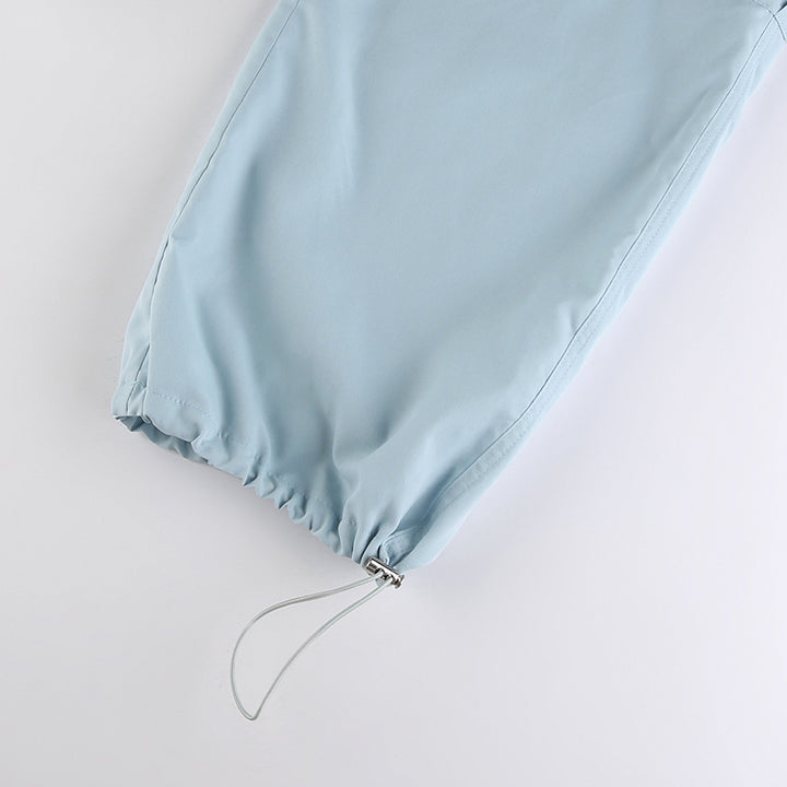 Un gros plan sur un pantalon cargo baggy bleu ciel pour femme avec élastique à la taille et aux chevilles. Fabriqué en polyester et spandex légers. Tailles disponibles : S à L.