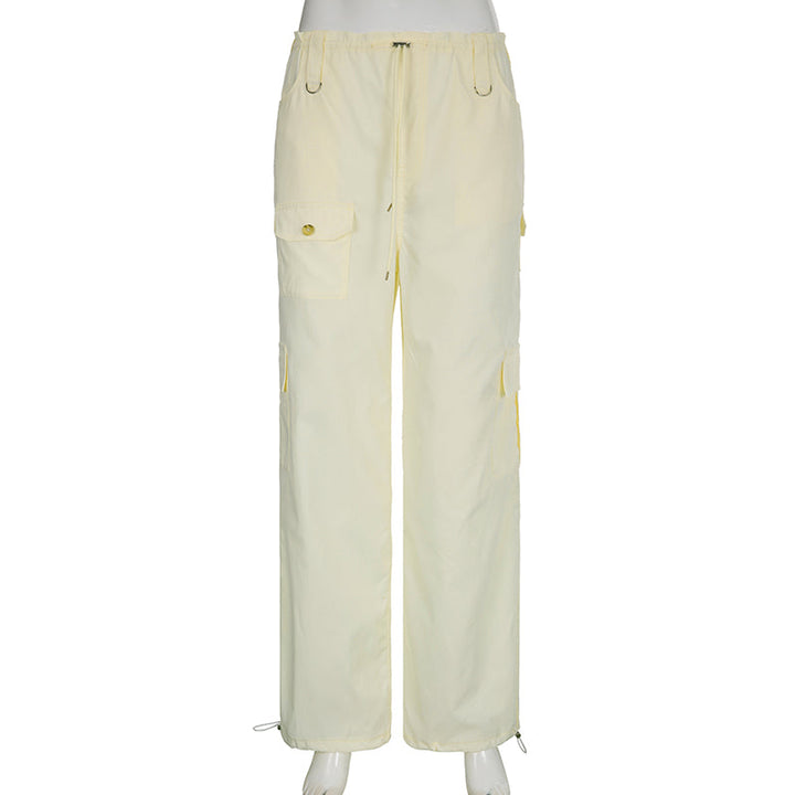 Un mannequin porte un pantalon cargo baggy taille basse élastique pour femme en blanc cassé. Le pantalon est fabriqué en polyester et spandex légers, offrant un ajustement confortable grâce à l'élastique à la taille. Son style baggy avec un élastique à la cheville lui donne une allure tendance. Disponible du S au L.