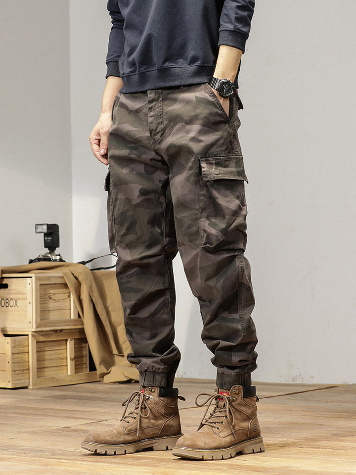 Un homme portant un pantalon cargo gris camo avec des bottes.