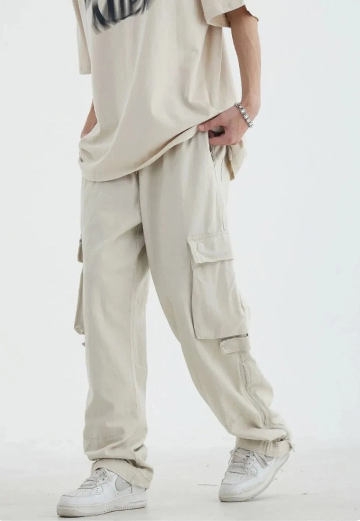 Un homme portant un pantalon blanc cargo HOUZHOU pour homme, style safari décontracté, avec poches zippées.