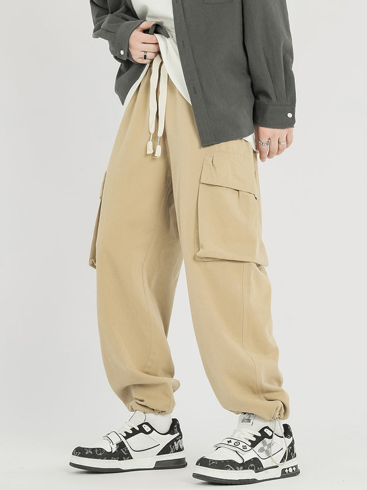 Un homme porte un pantalon cargo baggy en coton beige avec des chaussures.