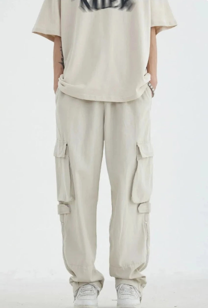Un homme portant un t-shirt et un pantalon cargo blanc HOUZHOU pour hommes, style streetwear japonais vintage, décontracté et ample, avec poches à fermeture éclair. Matière : 100% coton. Tailles disponibles : du M au 2XL.
