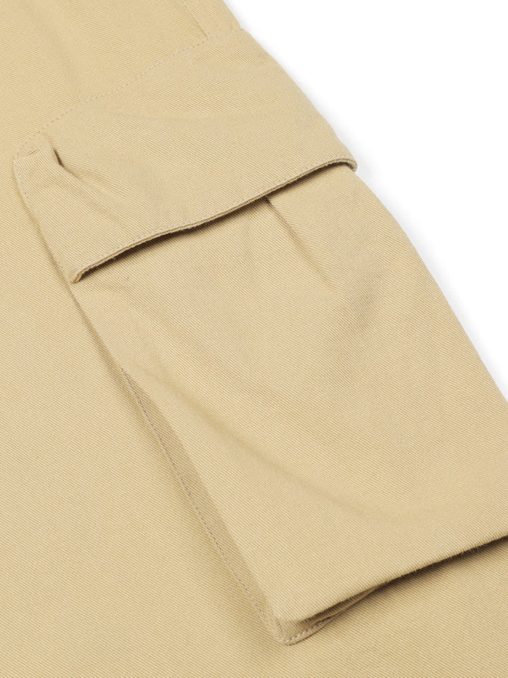 Un pantalon cargo baggy en coton beige pour homme avec une poche rapprochée. Coupe ample et confortable avec taille élastique et cordon de serrage. Ourlet élastique pour un ajustement personnalisé. Disponible du S au 2XL.