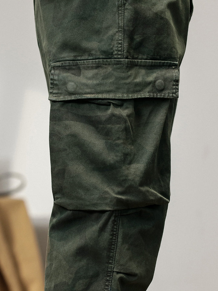 Un gros plan sur une poche de pantalon cargo kaki pour homme, avec une coupe large resserrée aux chevilles. Fabriqué à partir de 100% coton pour un confort optimal et une excellente durabilité. Disponible en tailles US 28 à 38.