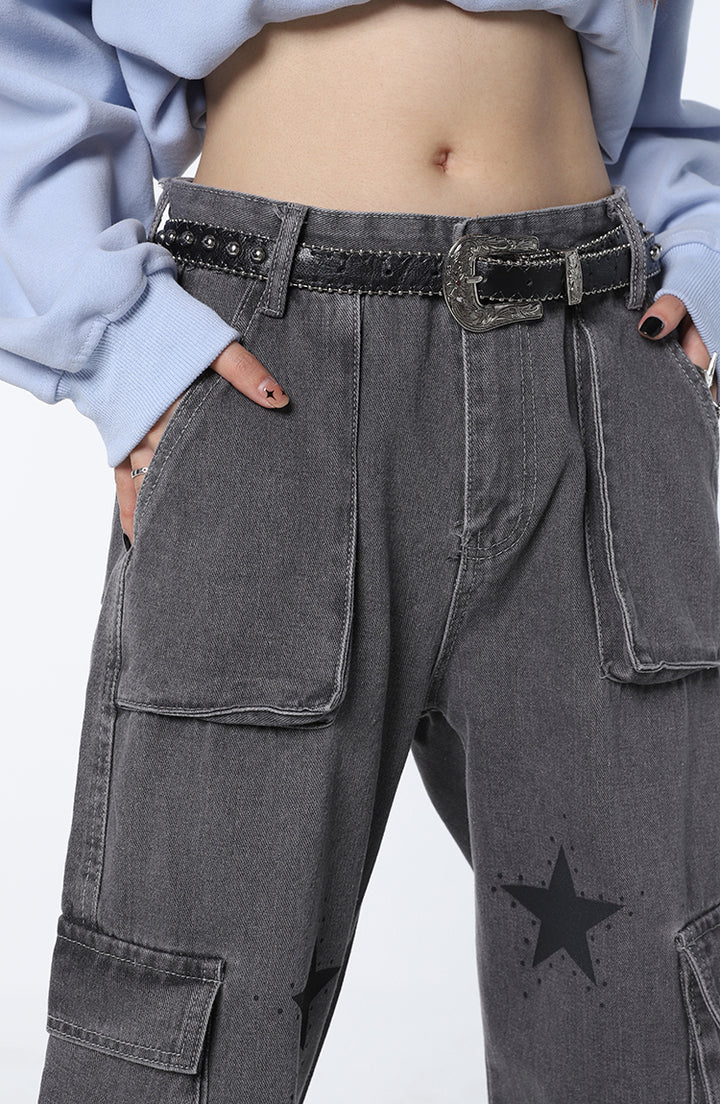 Une personne portant un jean cargo baggy étoiles gris pour femme avec une ceinture. Le jean a une coupe baggy qui souligne la taille et offre un confort maximal. Il est doté de multiples poches pratiques. Disponible du S au L.