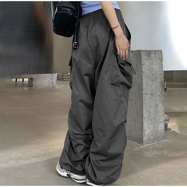 Une personne portant un pantalon cargo baggy léger gris pour femme. Coupe confortable avec élastique à la taille et aux chevilles. Poches latérales ajoutant une touche street et féminine. Disponible du S au 3XL.