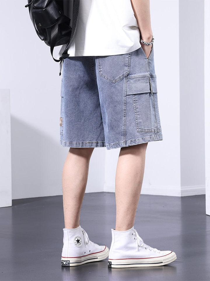 Un homme portant un short cargo en jean bleu clair et des baskets blanches.