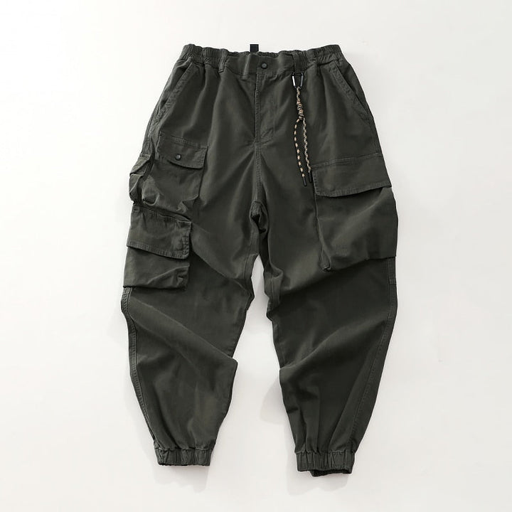 Un pantalon cargo baggy avec poches asymétriques - Kaki - Homme. Coupe audacieuse et masculine. Tissu 100% coton pour durabilité et confort. Tailles disponibles: M à 3XL.