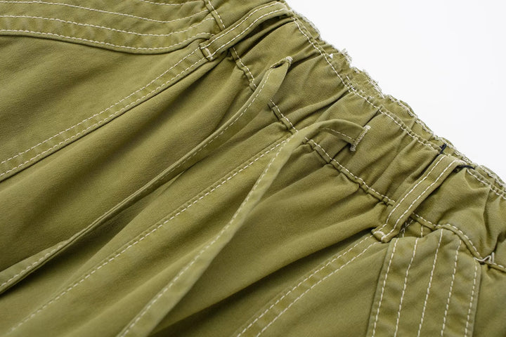 Pantalon cargo vert avec coutures blanches - Femme. Style urbain féminin avec jambe large ajustable. Disponible du XS au L.