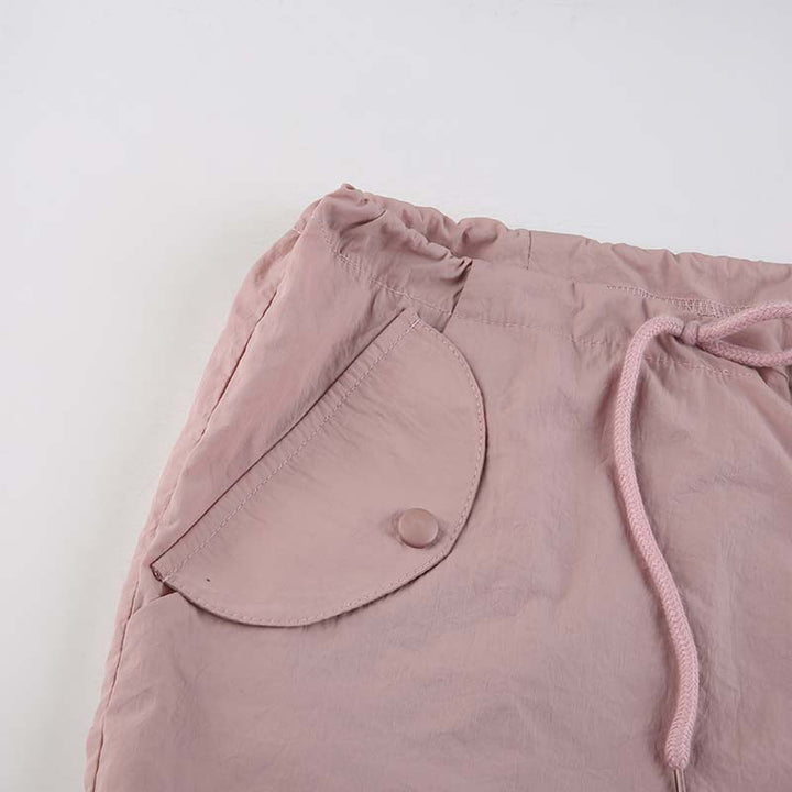 Un pantalon cargo rose avec une poche en gros plan et une jambe large finie par un élastique à la cheville. Taille basse et style baggy pour une allure urbaine et féminine. Disponible du S au L. Matières : Polyester, Spandex. Confortable et léger pour une journée en toute aisance.