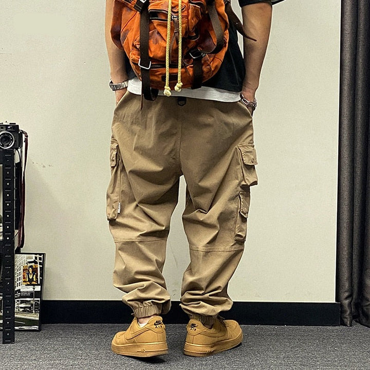 Un homme portant un pantalon cargo baggy avec des poches asymétriques - Beige.