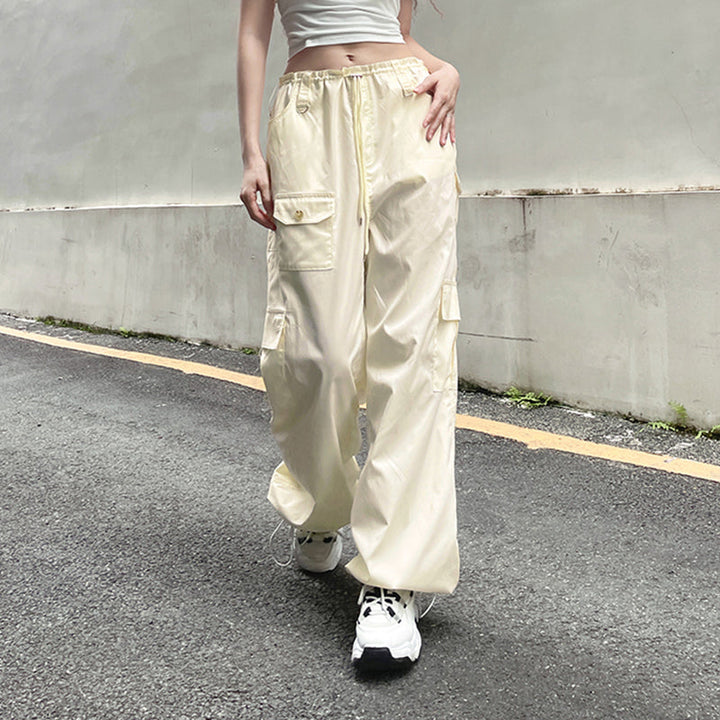 Une femme portant un pantalon blanc baggy avec taille basse élastique. Style street et décontracté, parfait pour un look urbain. Disponible en blanc cassé du S au L.