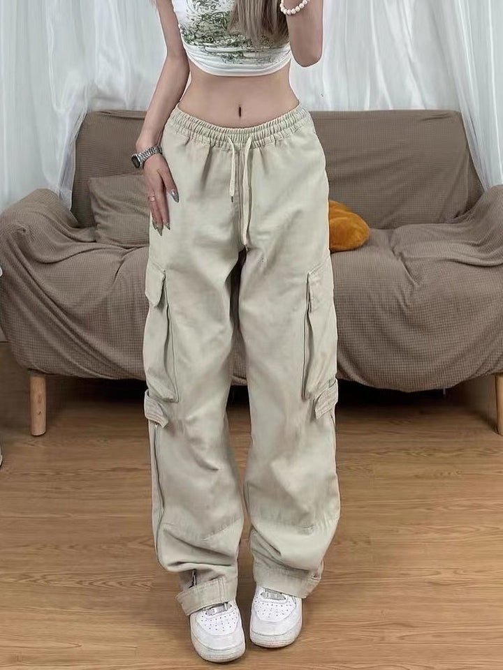 Une femme portant un pantalon cargo baggy à fermeture éclair beige pour femme avec des chaussures blanches.