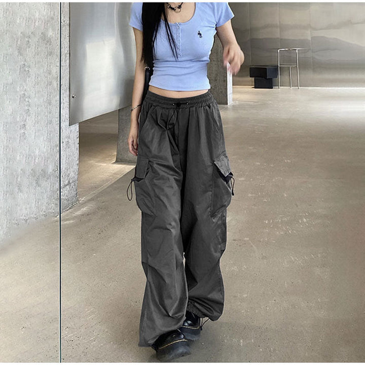 Une femme portant un pantalon cargo baggy léger gris avec des poches latérales. Coupe décontractée et confortable, idéale pour un look street et féminin. Disponible du S au 3XL. (Cargo District)