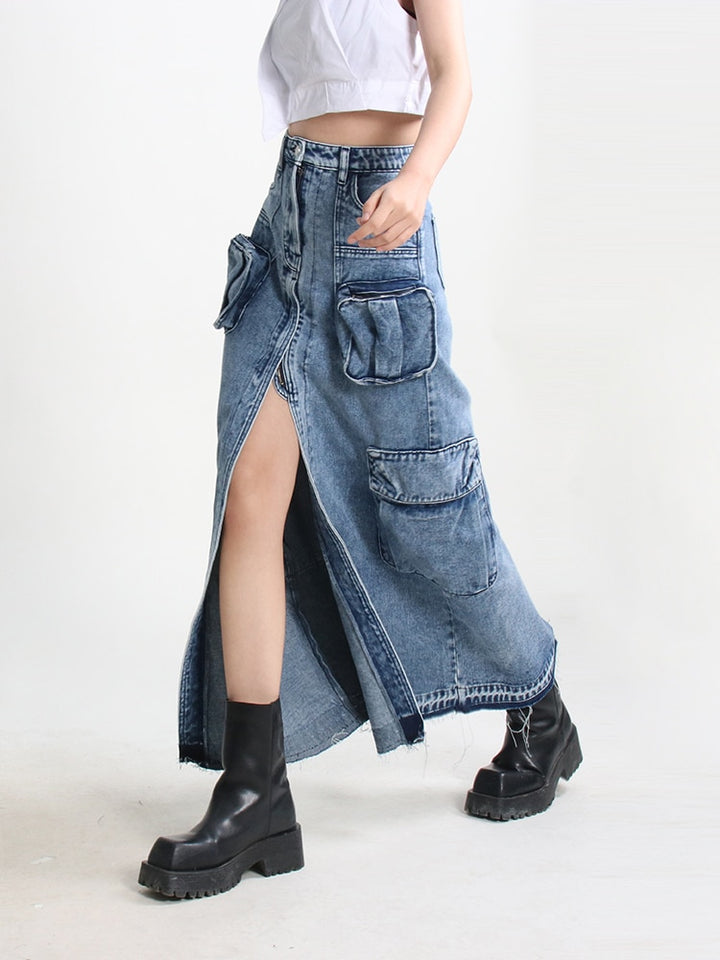 Une femme portant une jupe jean longue fendue multipoches bleue, ajoutant une touche urbaine et tendance à son style. Cette jupe cargo taille haute en toile denim offre confort et liberté de mouvement avec son design évasé et sa fente. Les nombreuses poches ajoutent une fonctionnalité pratique. Disponible en tailles S à XL.