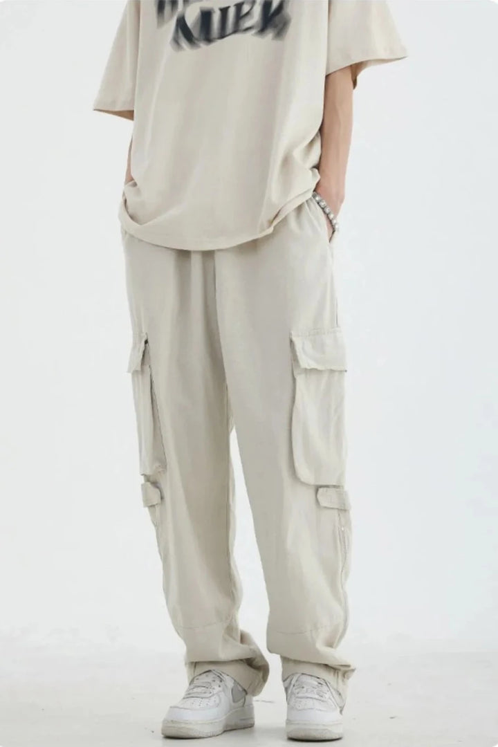 Un homme portant un pantalon cargo blanc avec poches, en coton 100%. Tailles disponibles : M à 2XL. Style décontracté, inspiré du streetwear japonais vintage.