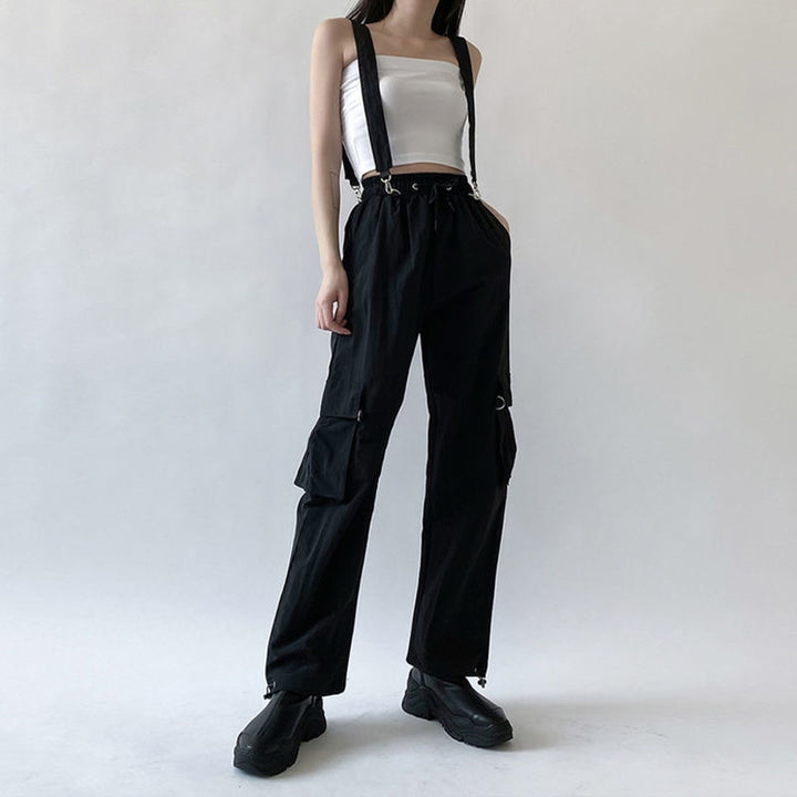 Une femme portant un pantalon cargo noir avec des sangles bretelles amovibles. Le pantalon est taille haute avec une coupe droite et une taille élastique pour un ajustement confortable. Disponible du S au 3XL.