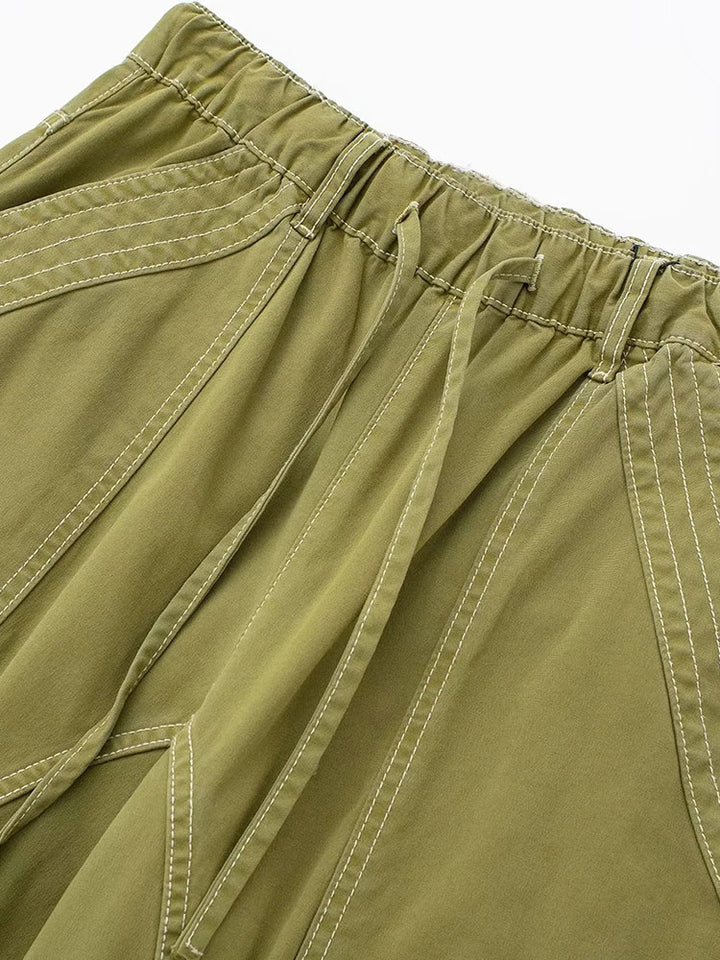 Un pantalon cargo vert avec coutures blanches, pour un look urbain féminin. Jambe large ajustable. Disponible du XS au L.