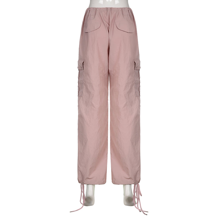 Un mannequin porte un pantalon cargo rose, taille basse et large, avec une jambe élastiquée à la cheville. Ce pantalon cargo féminin offre un style urbain et décontracté. Disponible du S au L. Matières : Polyester, Spandex. Cargo District, site de vente de vêtements de style cargo.