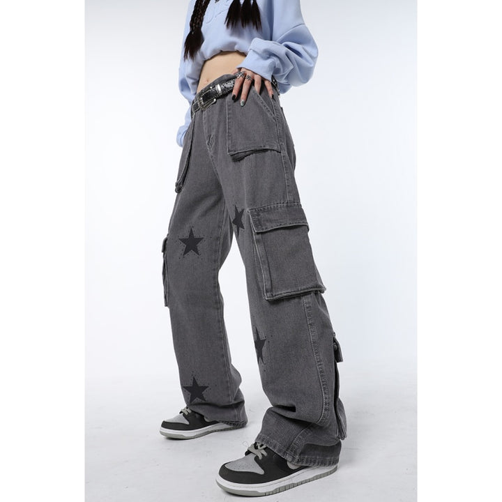 Une personne portant un pantalon cargo gris avec des étoiles. Coupe baggy, confortable et pratique avec plusieurs poches. Look streetwear chic et féminin. Disponible en tailles S à L.