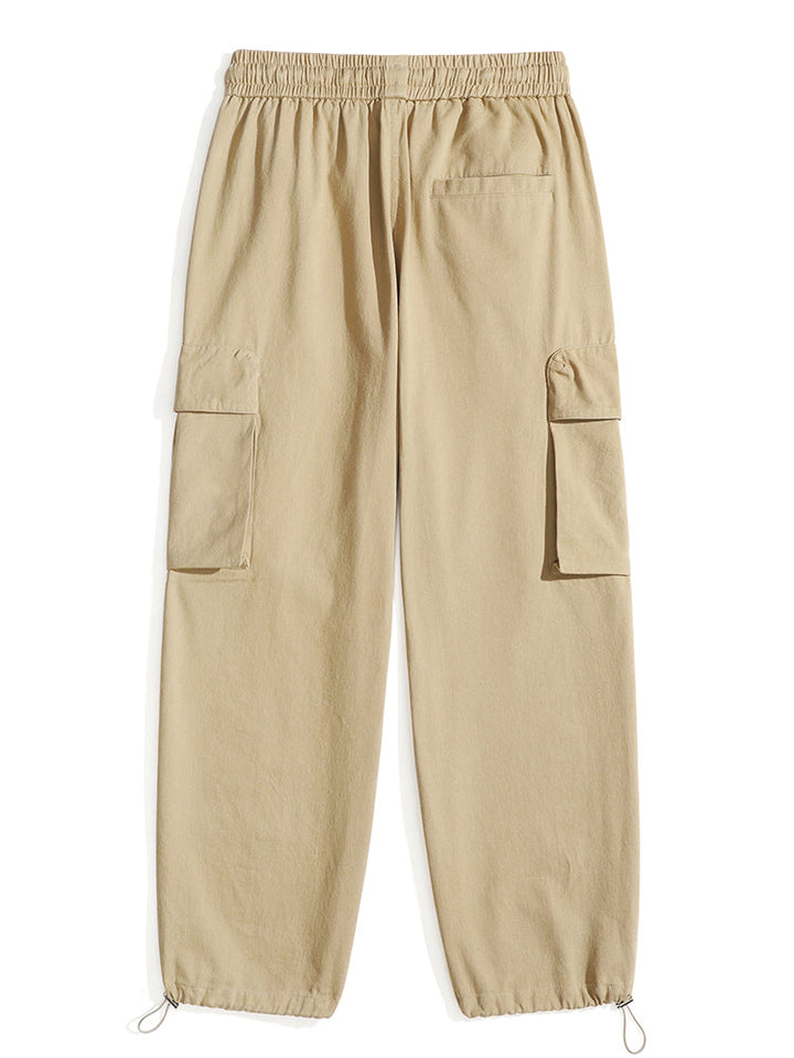 Un pantalon cargo baggy en coton beige avec poches pour homme. Coupe ample et confortable avec élastique à la taille et cordon de serrage. Disponible du S au 2XL.