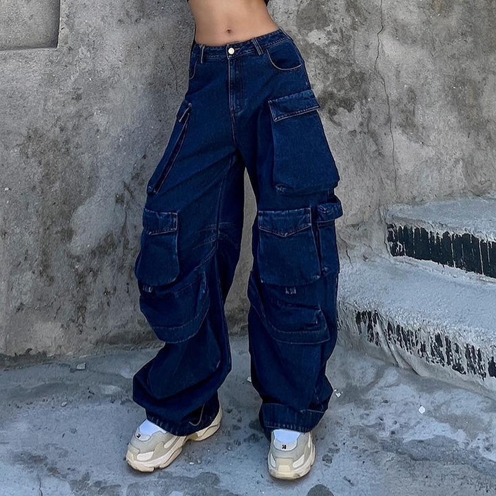 Une personne portant un jean cargo baggy bleu pour femme avec des jambes larges et évasées. Le jean a une taille basse et de nombreuses poches cargo sur les jambes. Disponible du S au 2XL.