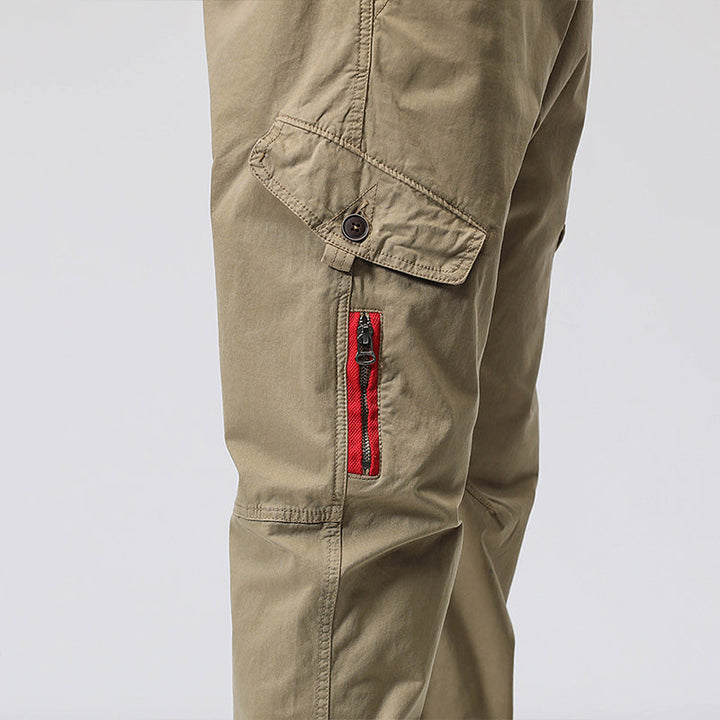 Un pantalon cargo coupe droite avec une fermeture rouge et une poche à l'avant. Couleur vert olive. Idéal pour une allure élégante et décontractée. Disponible en différentes tailles.