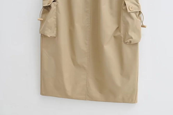 Une jupe cargo longue légère beige avec poches boutonnées, taille haute et fente arrière. Parfaite pour un look urbain estival. Disponible du S au L.