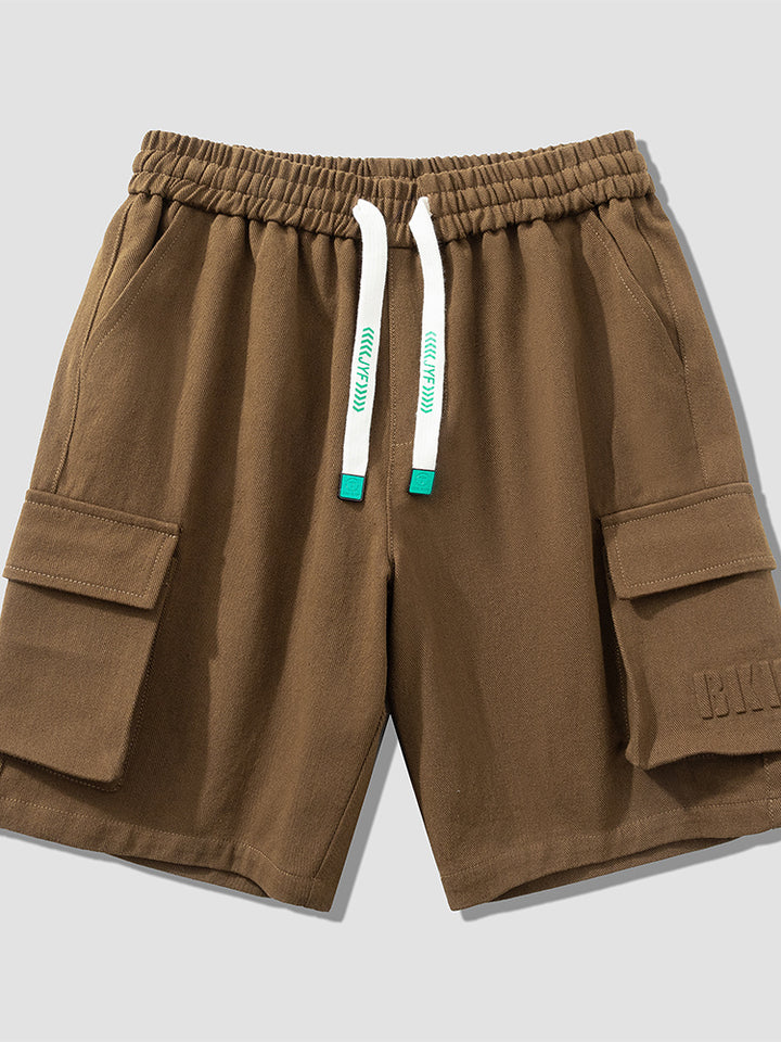 Un short cargo marron pour homme avec cordon blanc. Coupe large et longueur jusqu'aux genoux. Conçu en coton et viscose pour douceur et confort. Disponible du M au 8XL.