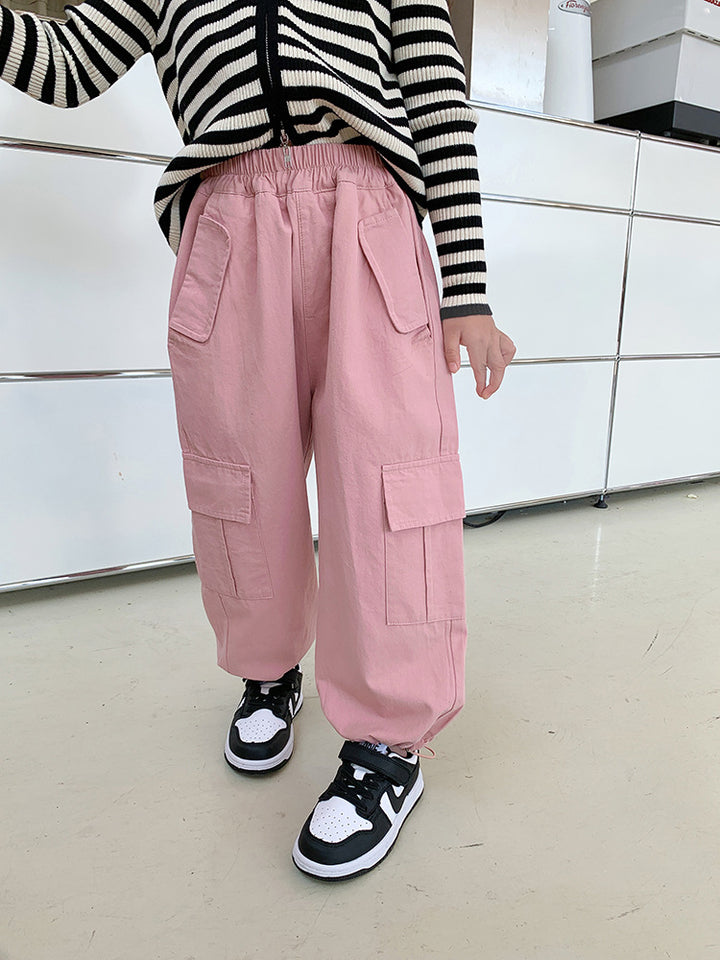 Une personne portant un pantalon rose cargo jogger large pour fille. Le pantalon est resserré aux chevilles et doté d'un élastique à la taille. Il présente des poches latérales pratiques. Disponible du 2 au 7 ans. Confortable et tendance.