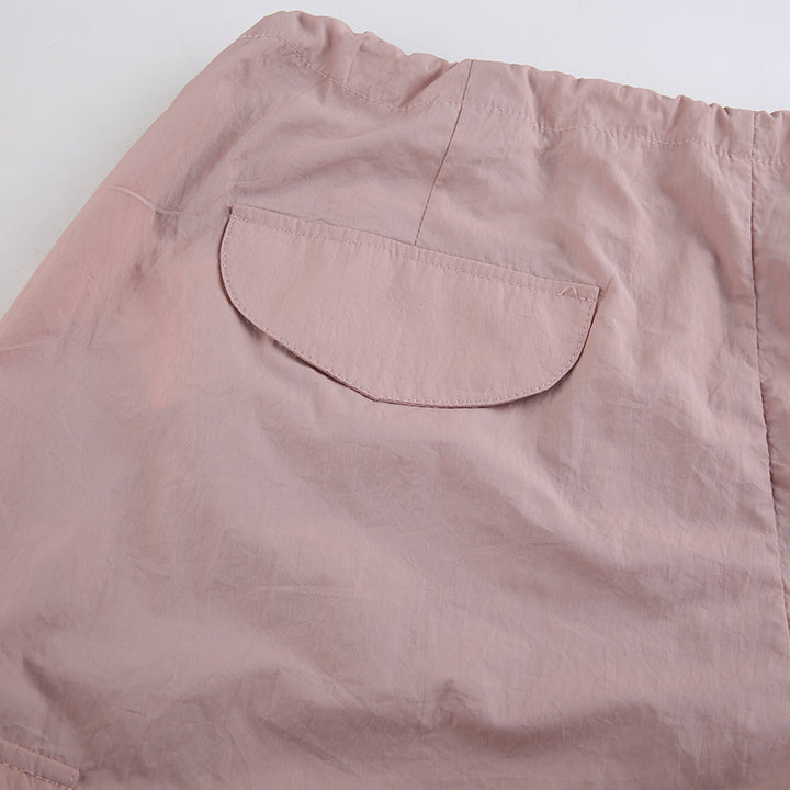 Un gros plan d'un short rose avec une poche. Pantalon cargo large taille basse - Rose - Femme. Confortable et urbain, ce pantalon cargo rose est idéal pour un look street. Disponible du S au L. Matières : Polyester, Spandex.