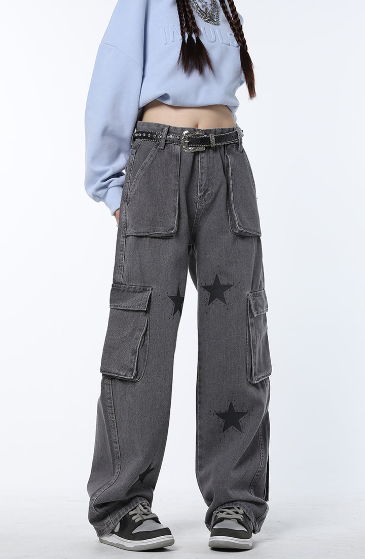 Une femme portant un jean cargo baggy étoiles gris avec poches latérales et à l'arrière de la jambe. Coupe confortable et taille soulignée. Look streetwear chic et féminin. Disponible du S au L.
