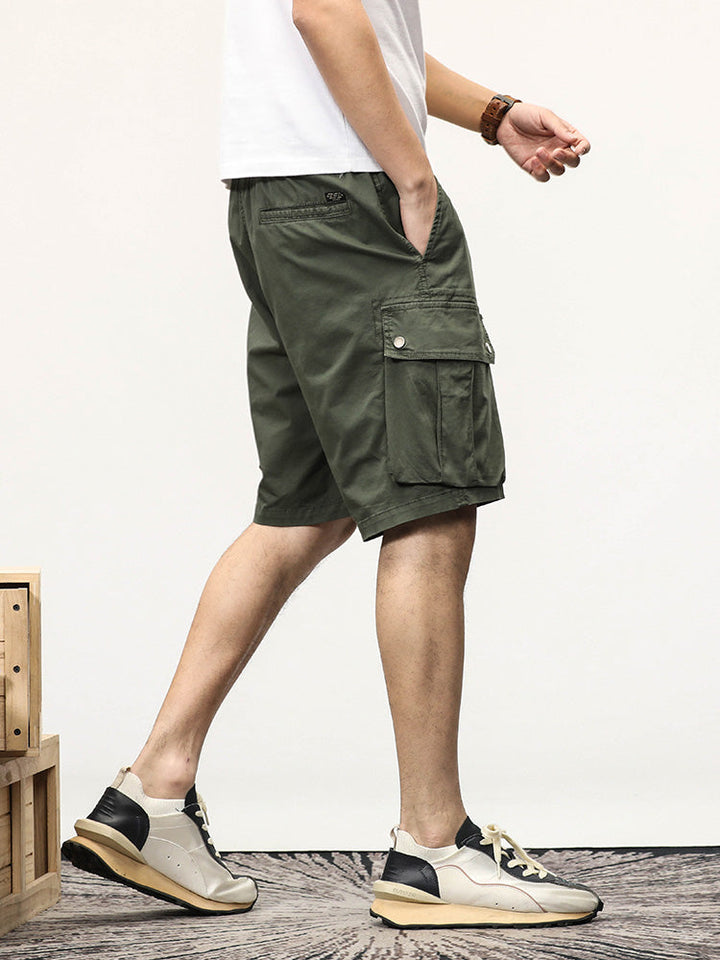 Un homme portant un short cargo coupe droite kaki avec des sneakers.