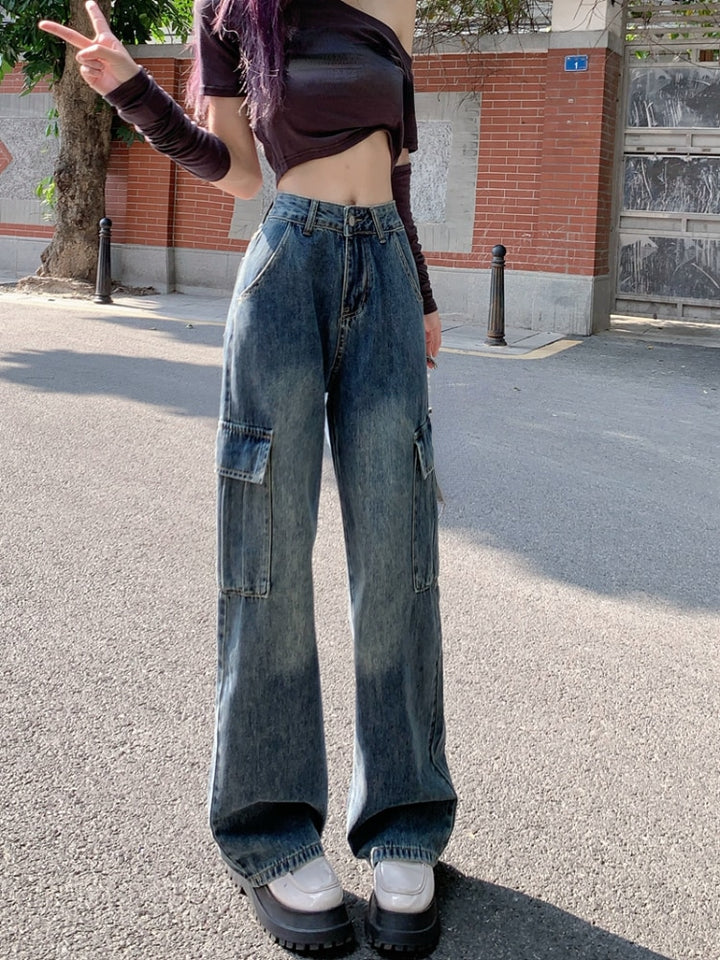 Une femme portant un jean cargo large taille haute bleu, avec des poches latérales cargo typiques du cargo. Le jean est disponible du S au XL et est fait de denim et de polyester. Parfait pour un style urbain unique.